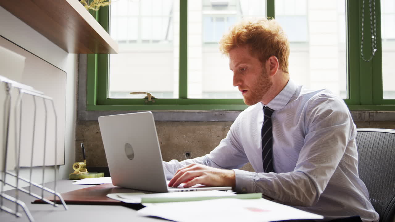 Red haired businessman working with laptop, close up