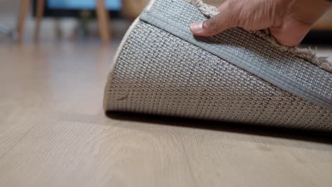 una persona colocando una alfombra en un piso de madera