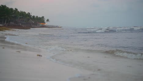 small waves rolling and breaking on beach shore during grey dim evening after sunset
