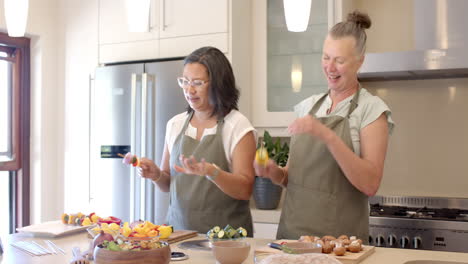 senior diverse women preparing fresh vegetables in modern kitchen, enjoying cooking, at home