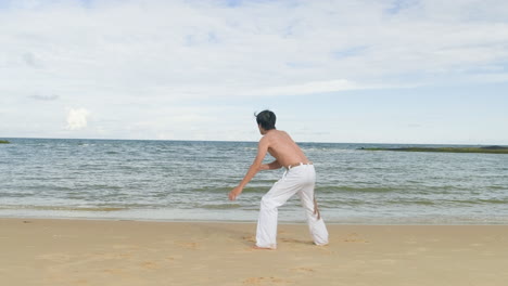 Guy-dancing-capoeira-on-the-beach