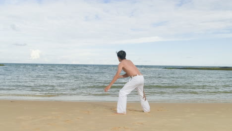 guy dancing capoeira on the beach