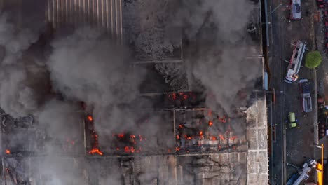 Vista-Aérea-Sobre-Un-Incendio-Industrial,-Camiones-De-Bomberos-En-El-Costado---De-Arriba-Hacia-Abajo,-Disparo-De-Drones