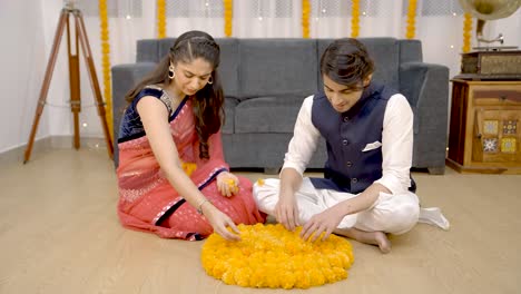 una linda pareja india haciendo rangoli