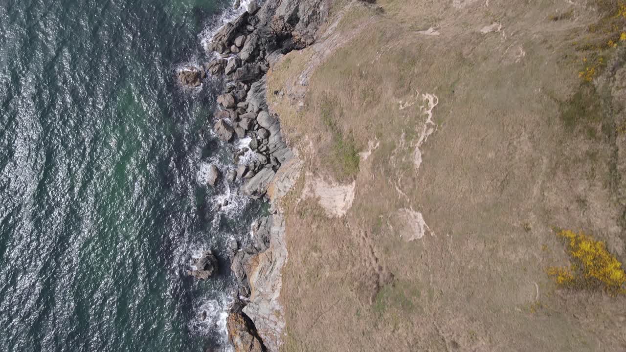 olas salpicando en la costa rocosa de howth, dublín, irlanda con vistas panorámicas de acantilados escarpados en verano