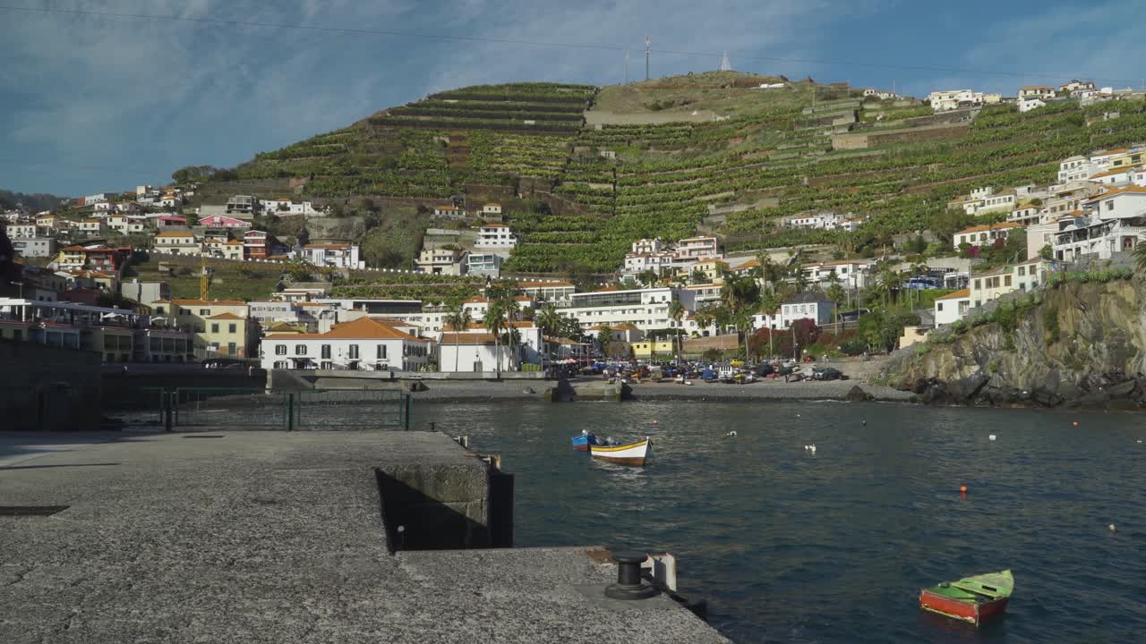 Fishing boats floating with Camara de lobos village in the background, Madeira island, Portugal.