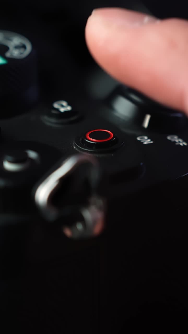 Macro close-up of a finger pressing the red record button on a mirrorless camera, starting video recording in a studio setup