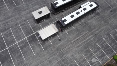 aerial view around workers cleaning and washing a tour coach after a live music trip - circling, drone shot