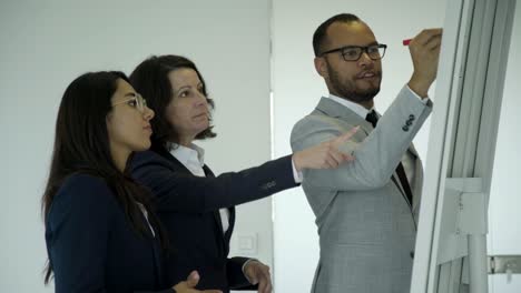 positivo hombre de negocios barbudo dibujando a bordo en la oficina