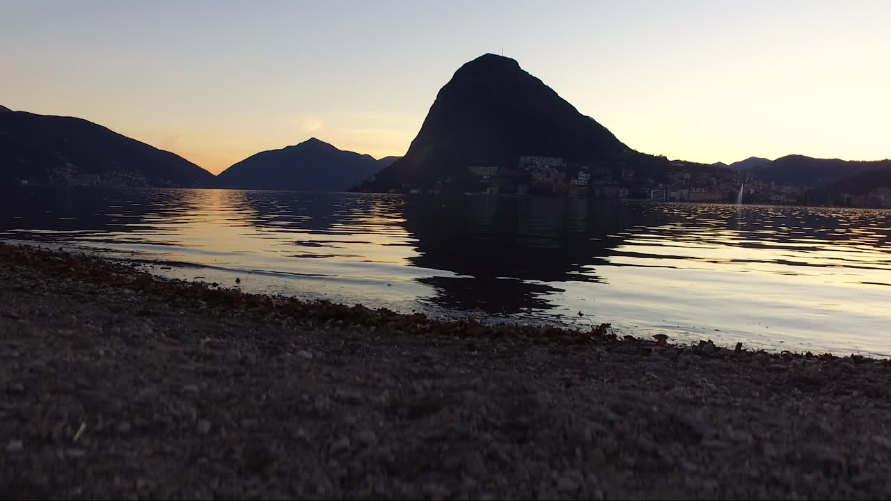 Drone che atterra su una spiaggia vicino a un lago e alle montagne