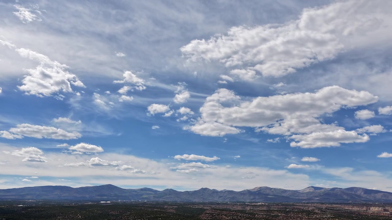 Splendido timelapse con drone mostra nuvole in movimento e luce solare nitida su un orizzonte di catena montuosa aspra. Il movimento cinematografico cattura la vasta scala di una natura selvaggia di alta quota nel sud-ovest.