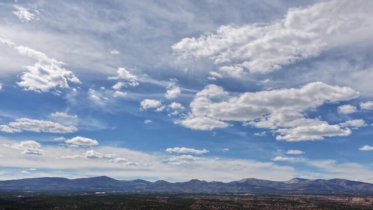 Impresionante timelapse de dron presenta nubes cambiantes y luz solar brillante y nítida sobre el horizonte de una escarpada cordillera. El movimiento cinematográfico captura la vasta escala de una zona salvaje de alta altitud del suroeste