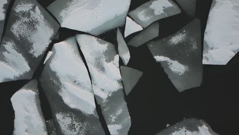 drone shot flying over frozen lake covered in ice and snow flying sideways pass chunks of ice