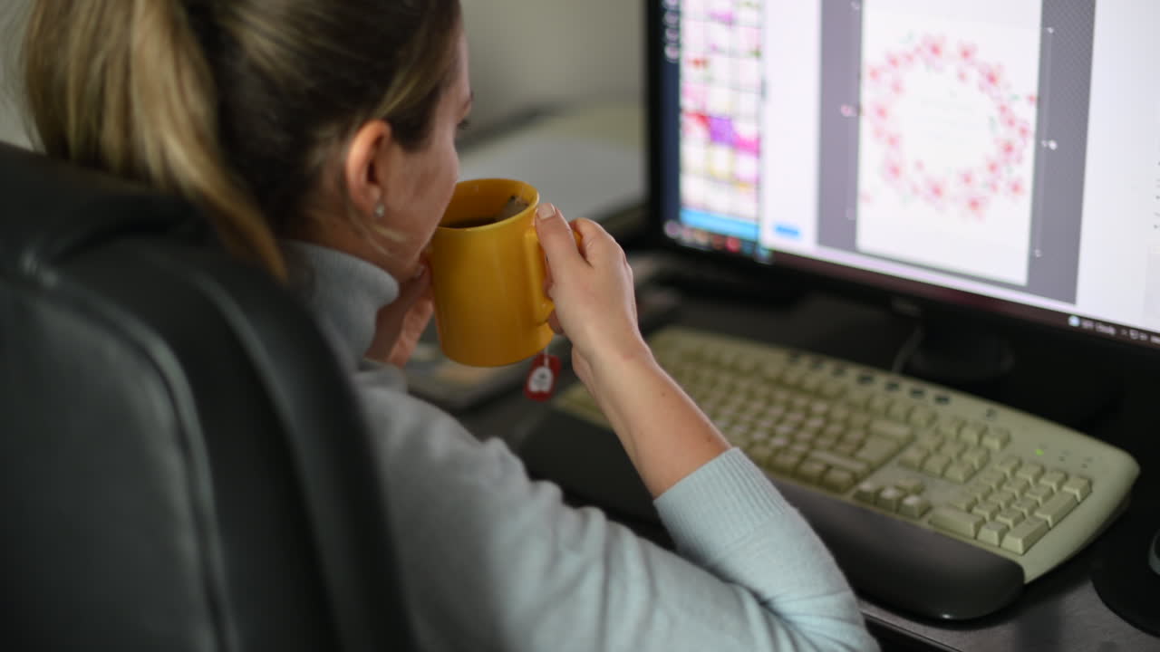 Woman designer drinking tea at the office and working on the pc