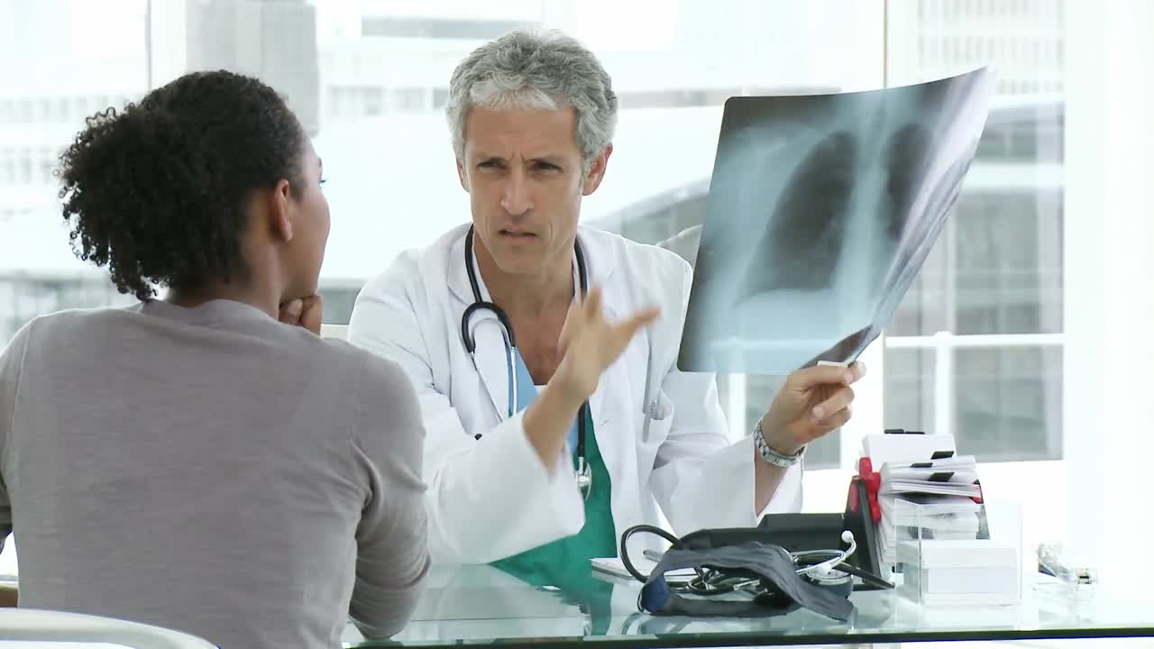 Male doctor and his patient looking at lungs Xray