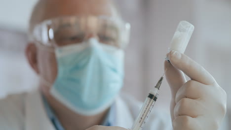 la mano del médico sostiene una jeringa y una botella azul de vacuna en el hospital. conceptos de salud y medicina. el médico dibuja la vacuna en la jeringa vial inyección de ampola de coronavirus covid-19. imágenes de alta calidad 4k