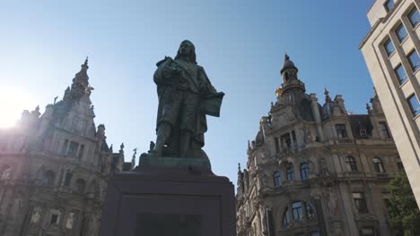 historic statue and ornate buildings under a blue sky at plaza teniers, antwerp