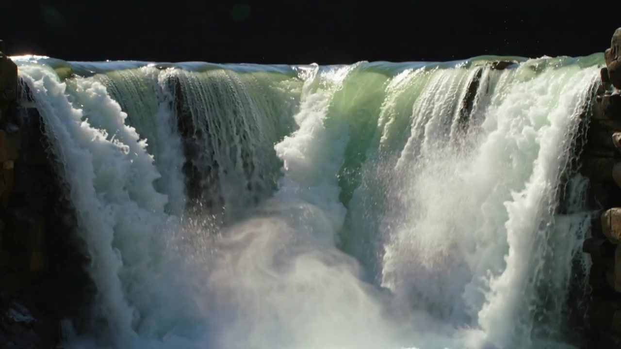 Reaching river brink causing waterfall plunging over ledge into churning plunge pool, spraying mist