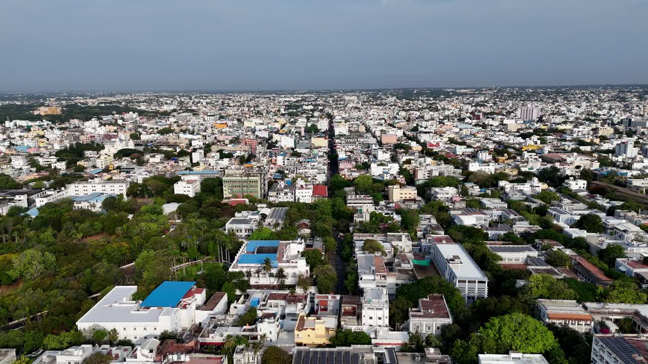A wide, high-angle aerial shot captures a densely populated urban area in Puducherry. Long road runs through the center of the frame urban planning, city life, population density, and regional travel