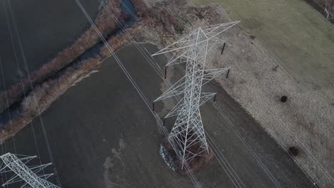 Aerial-Drone-Dolly-Right---Pair-of-High-Voltage-Electrical-Towers-from-Above---Winterish-Landscape