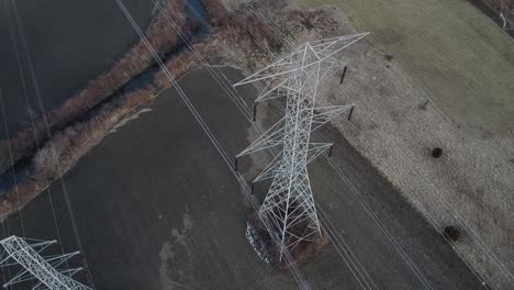 aerial drone dolly right - pair of high voltage electrical towers from above - winterish landscape