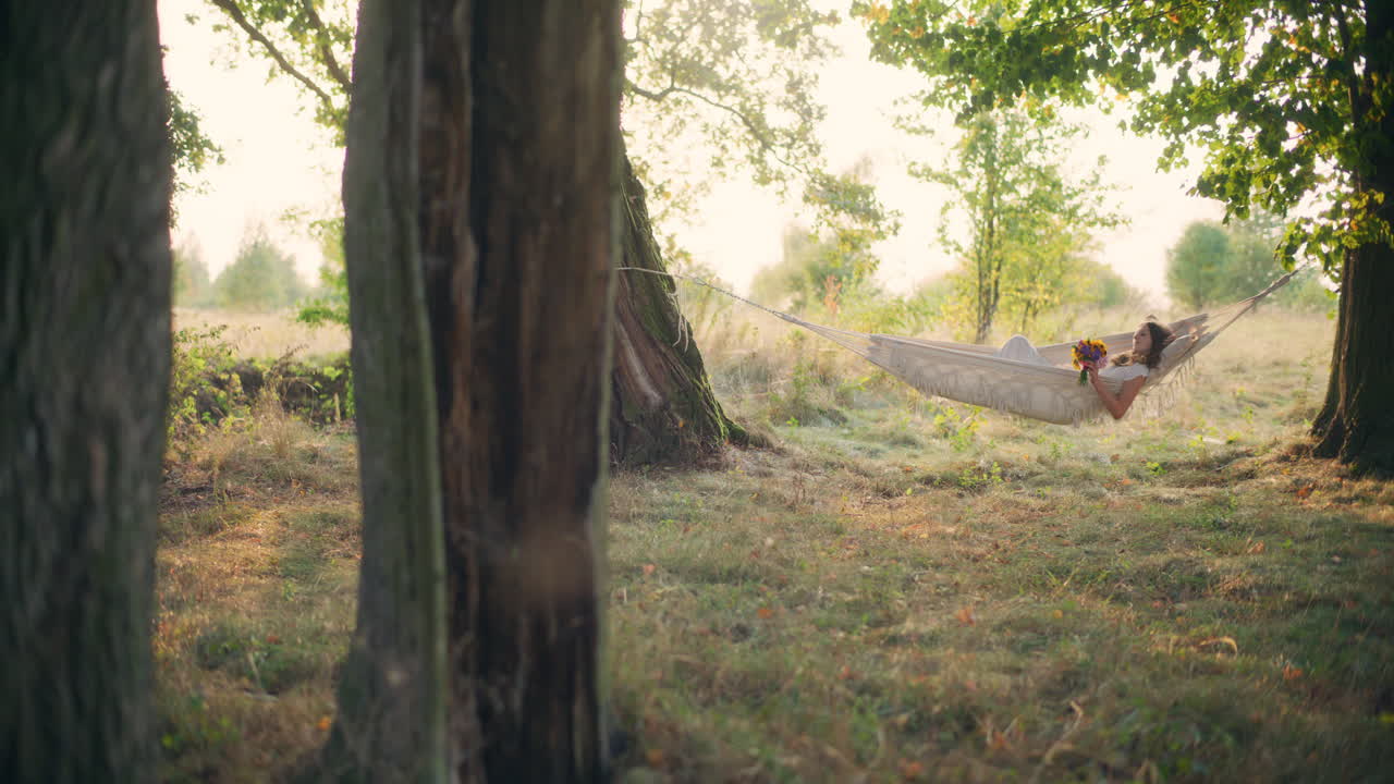 Peaceful girl relaxing in hammock among trees
