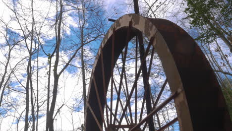 an old rusted waterwheel turning against the sky on a forest at georgia