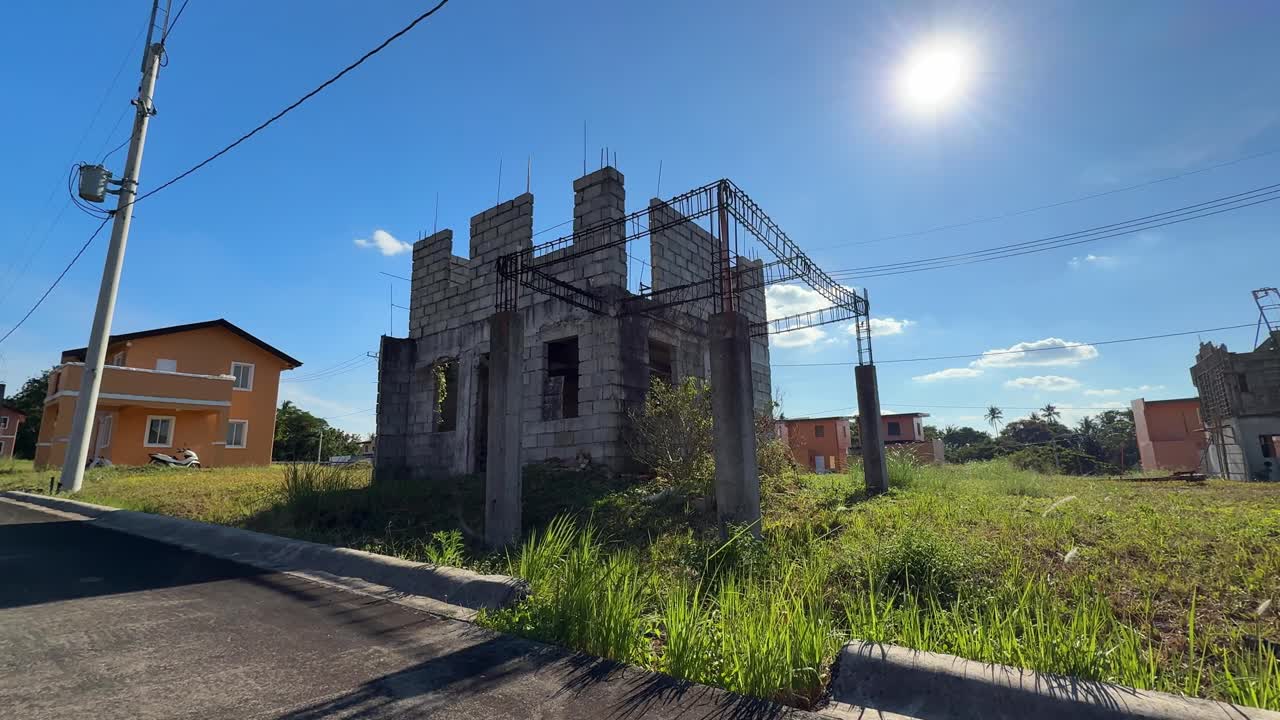 Vista a livello del suolo di una struttura portante in costruzione accanto a moderne case finite in un villaggio sviluppato presso Camella Homes Alfonso Cavite, Filippine.