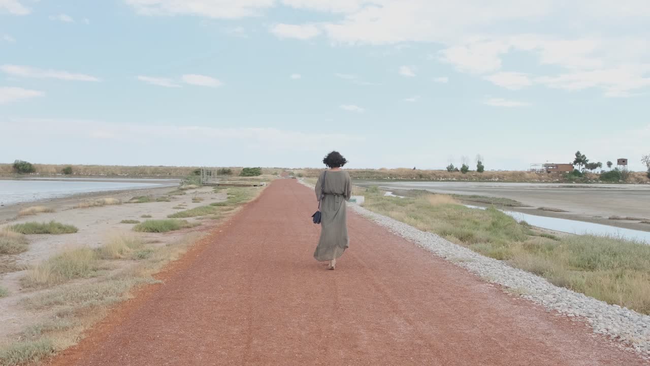 Glamorous Career Woman In Long Dress And High Heels Sandals With Black Shoulder Bag Walking Alone In The Walkway - long slowmo shot