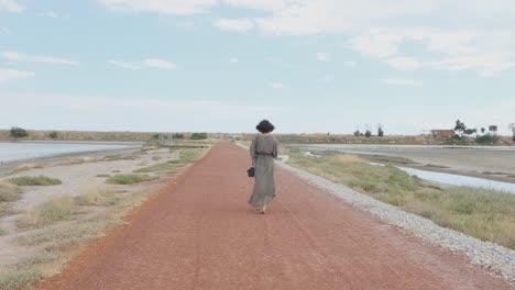 Glamorous-Career-Woman-In-Long-Dress-And-High-Heels-Sandals-With-Black-Shoulder-Bag-Walking-Alone-In-The-Walkway---long-slowmo-shot