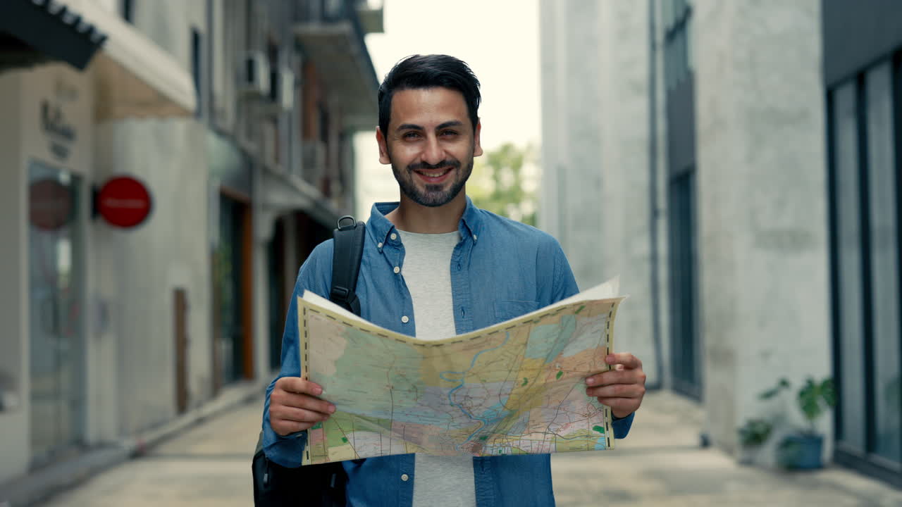 Happy Tourist Man Looking at Map and Smiling in City Street