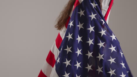 close up studio shot of woman wrapped in american flag celebrating 4th july independence day 3