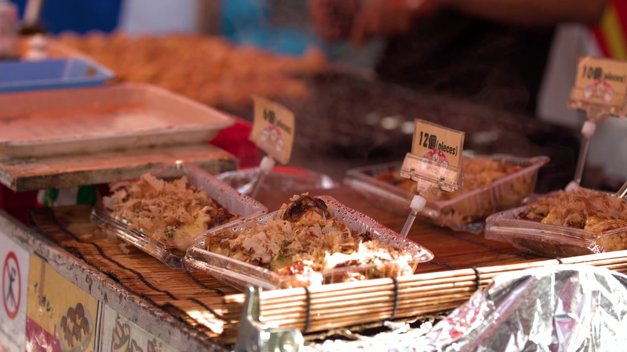 Close-up takoyaki panas dengan serutan bonito yang menari di kedai pasar terbuka Jepang
