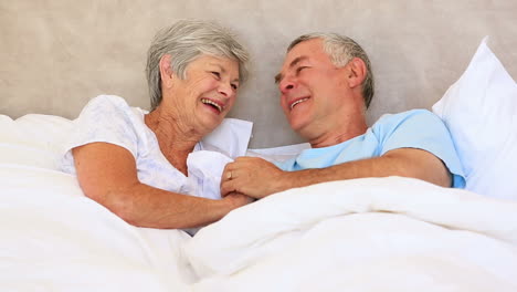 Feliz-Pareja-De-Ancianos-Tumbados-En-La-Cama-Charlando