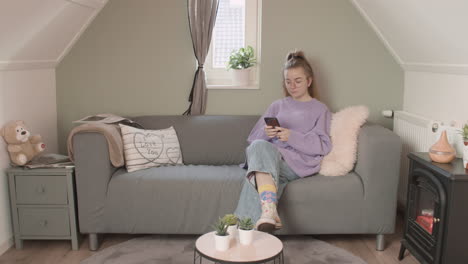 girl sitting on couch with her phone, wide