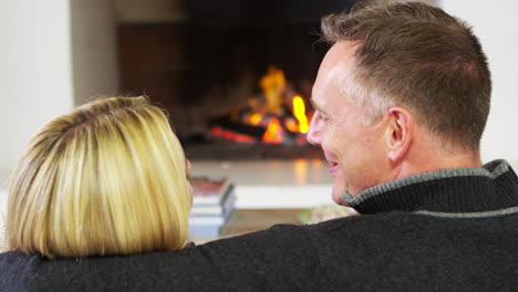 couple sitting on sofa in lounge next to open fire