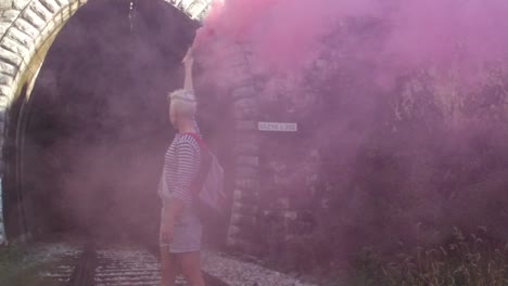 person releasing pink smoke in a tunnel