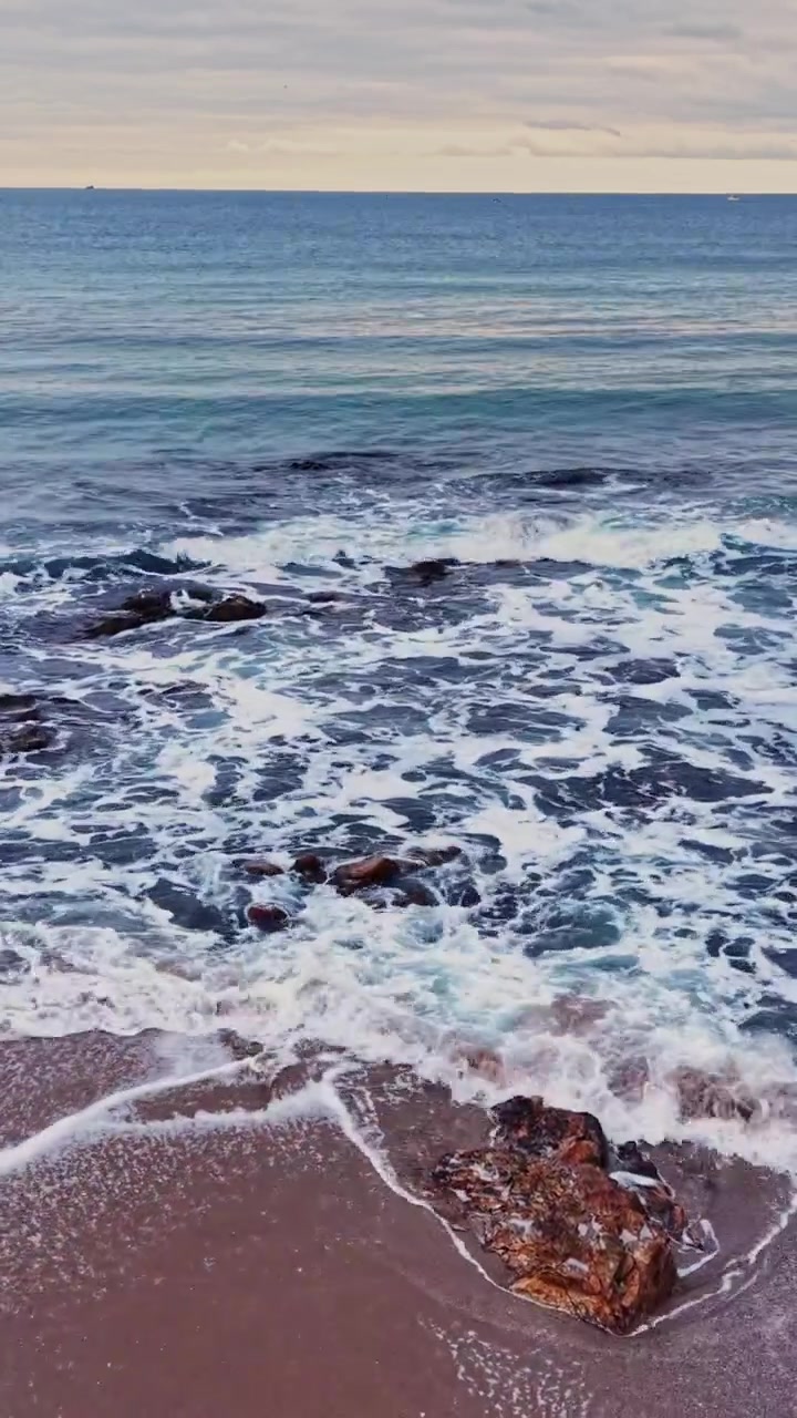 Vista delle onde calme dell'oceano che si infrangono sulla costa rocciosa al tramonto