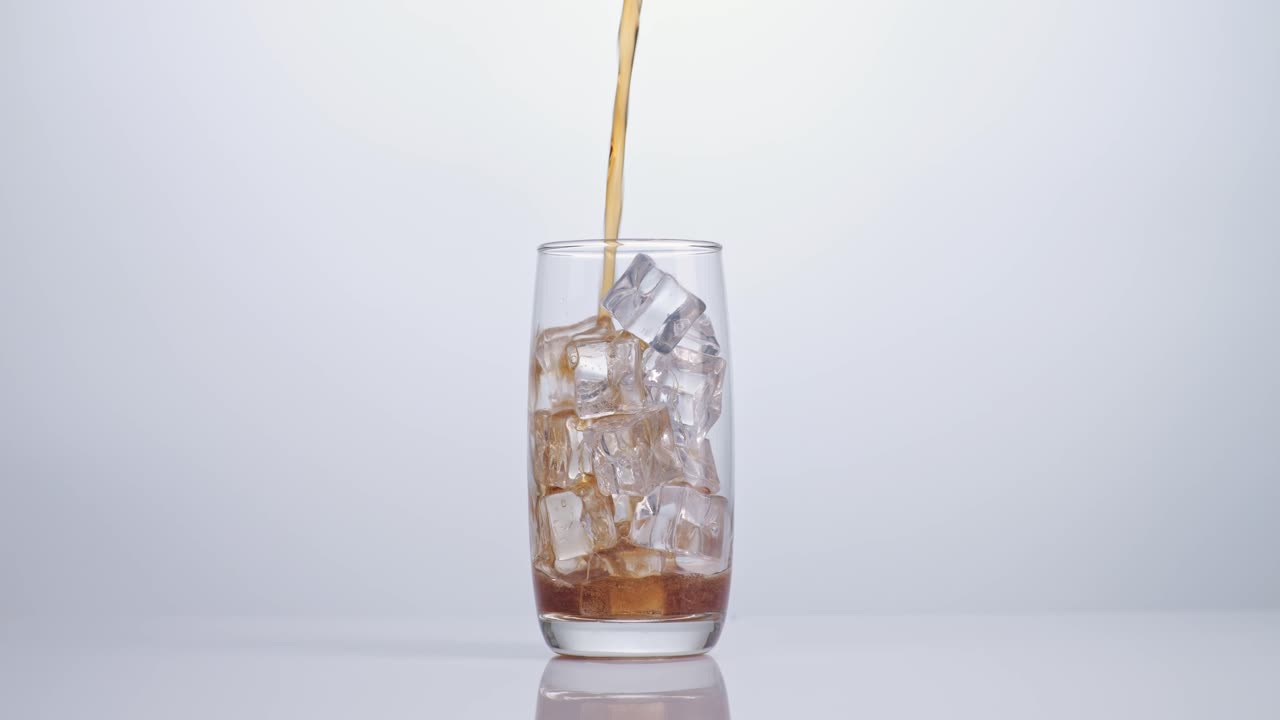 cola fresca que se vierte en el vaso con cubos de hielo en fondo blanco