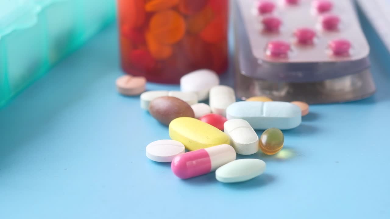 primer plano de varias pastillas, tabletas y un termómetro