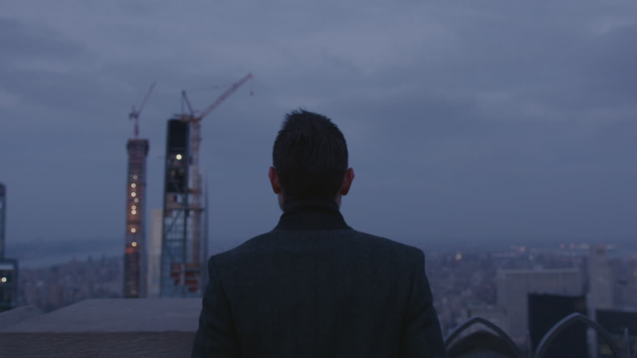 A man stands outside in a city at night