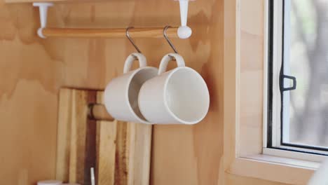 person grabbing coffee mug in wooden tiny cabin kitchen