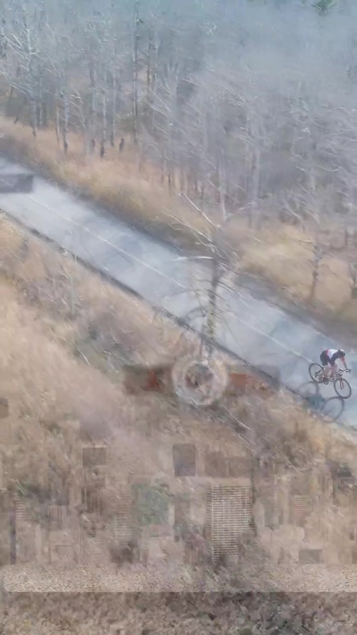 Video verticale: Ciclista uomo che pedala su un sentiero, passando accanto a un albero, con overlay di UI tecnologica su vetro.