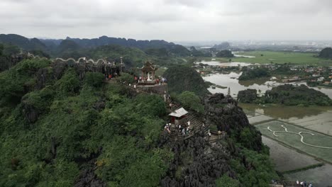 Hermosas-Montañas-Y-Gente-Subiendo-Escaleras-A-Un-Templo-En-La-Cima-De-La-Montaña-Nin-Bihn,-Hang-Mua,-Vietnam