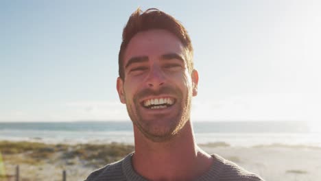 happy caucasian man standing and smiling by the sea