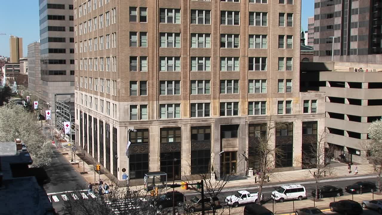 카메라가 오래된 고층 사무실 건물의 아래쪽에서 깃대를 포함하여 위쪽으로 이동합니다.