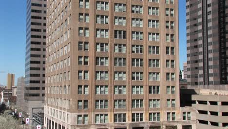 the camera pans from the bottom of an older highrise office building to the top including flagpole