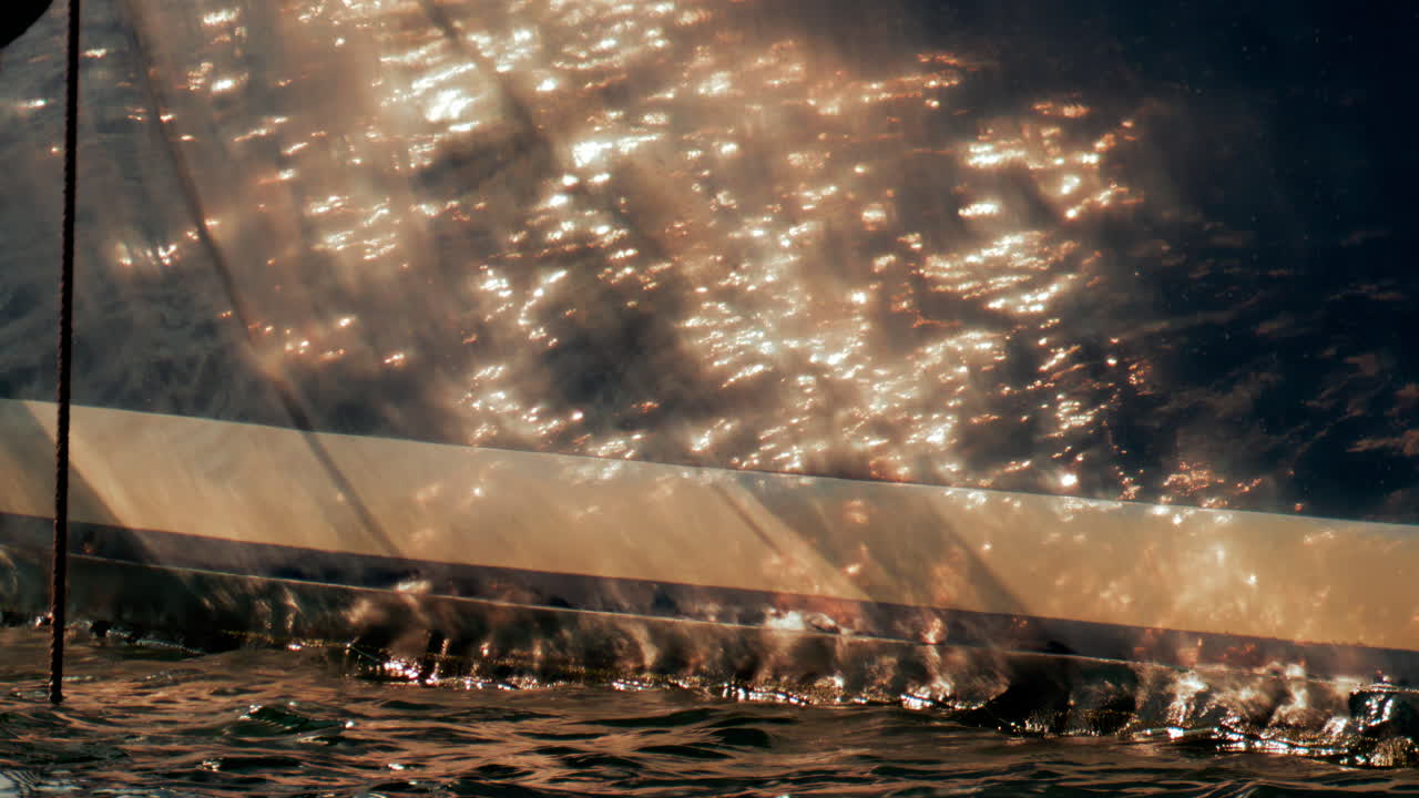 Sunlight dances on the polished side of a luxury yacht, reflecting warm golden tones across gentle waves