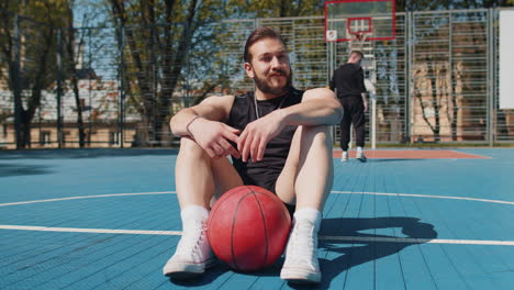 portrait of tired smiling athletic lebanese man in sportswear relaxing after playing basketball game