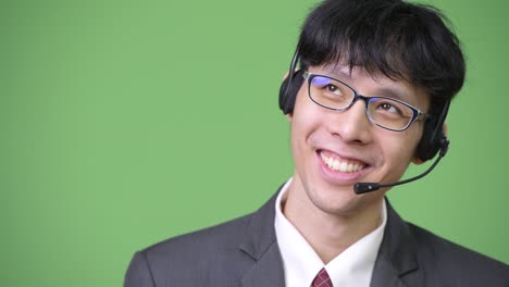 joven empresario asiático feliz pensando y trabajando como representante de un centro de llamadas